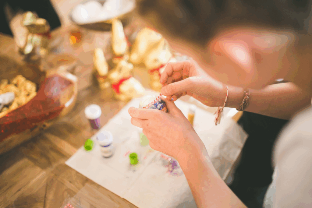 Blurred image looking over the shoulder of a child making a paper craft with glue and paint at a school holiday programme.